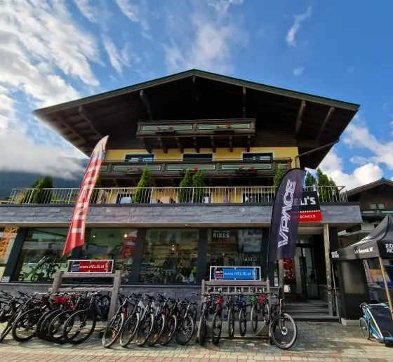 Das Haus an der Dorfstraße 165 von vorn: Balkon aus Holz, darunter die Schaufenster von SPORT 2000 Hinterglemm